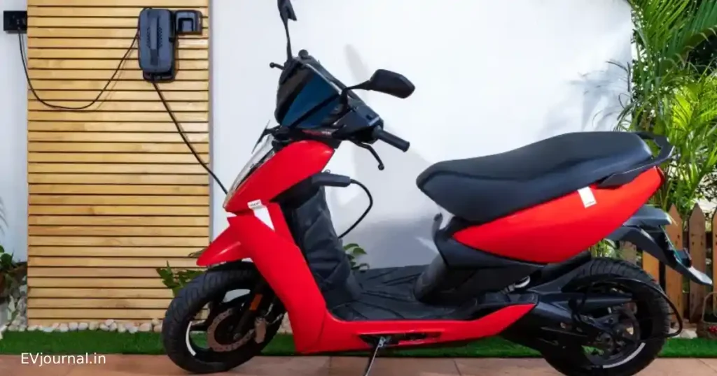 Red electric scooter connected to a home charging point in India.