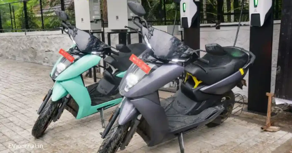 Two electric scooters parked at a public EV charging station in India.