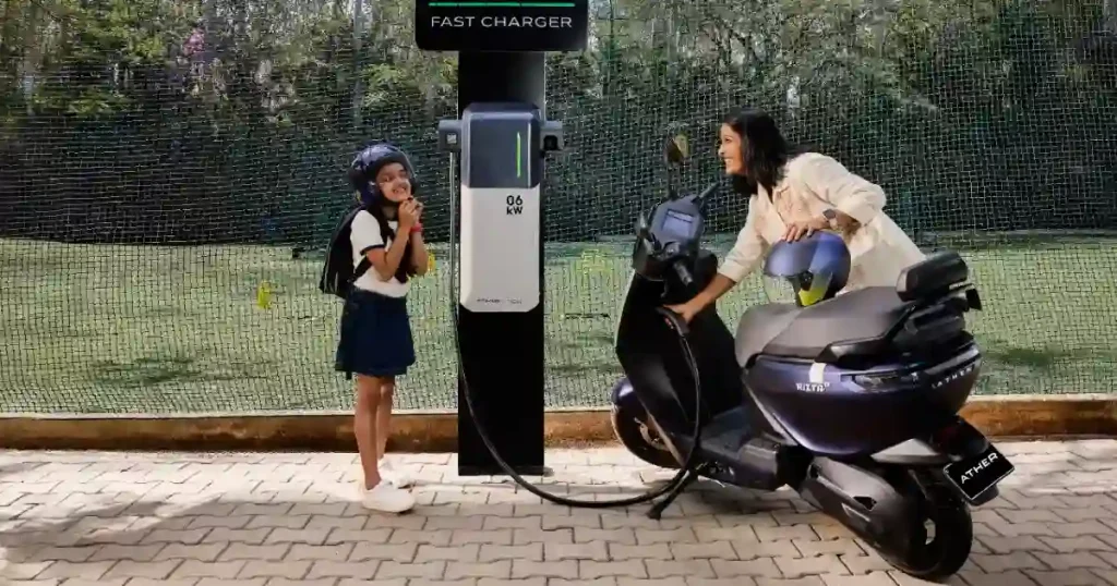 Woman charging an Ather Rizta electric scooter at a public EV charging station in India.