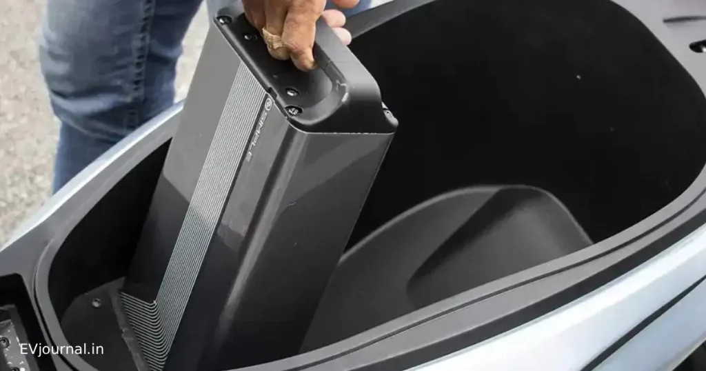 Removable electric scooter battery being lifted from the under-seat storage compartment.