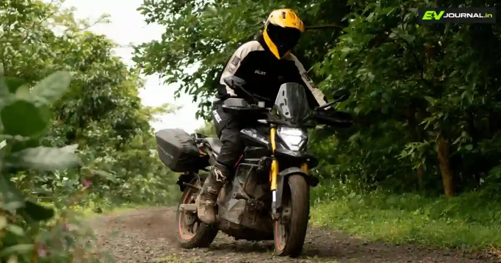 Ultraviolette X-47 Venom electric motorcycle with a rider wearing a yellow helmet on a forest trail